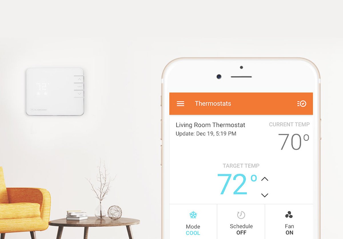 Alarm.com-app-on-phone-in-front-of-room-with-security-panel-on-wall