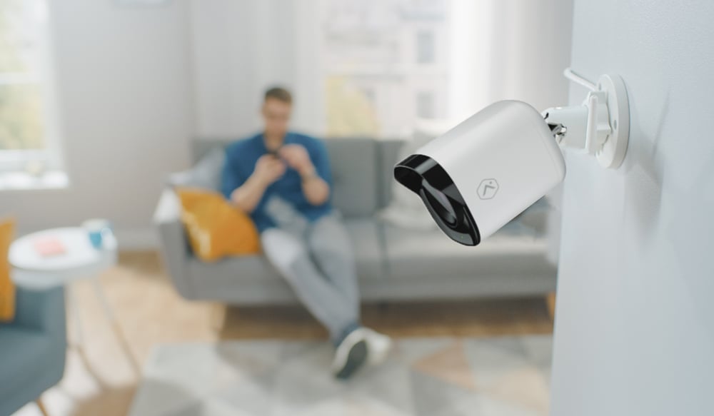 White male adjusting smart camera and monitoring camera on his phone on the couch