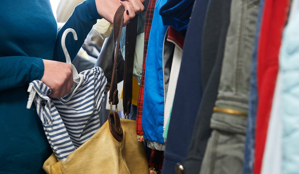 woman stealing striped shirt and putting it in her purse