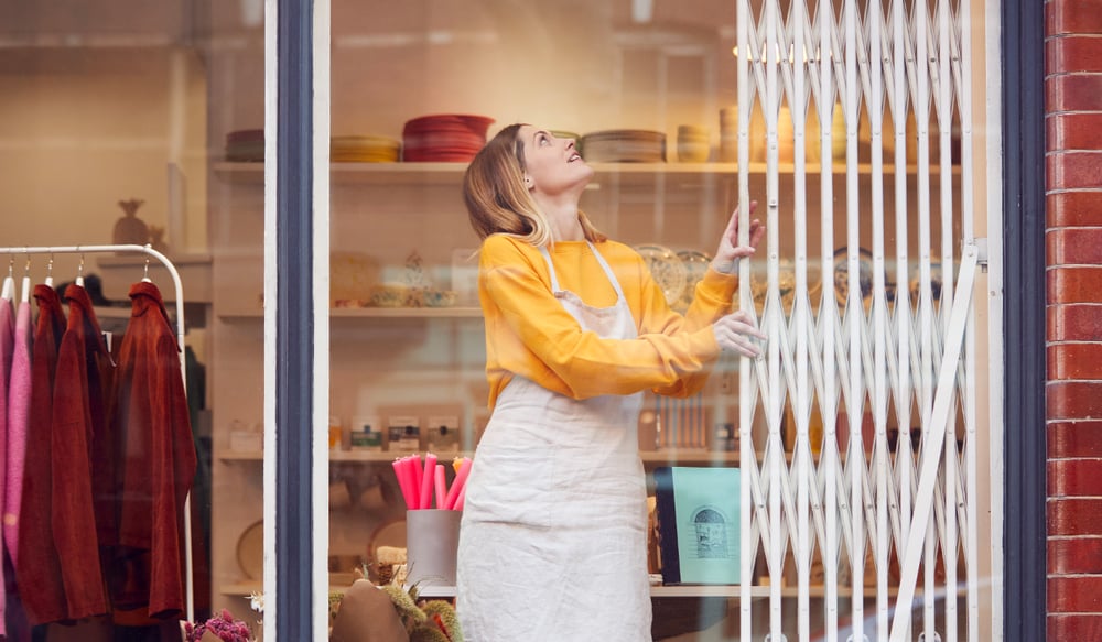 Woman closing security cage on small clothing store